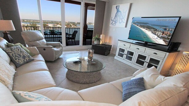 Una sala de estar con un sofá, una mesa de centro, un televisor y un balcón con vista a la playa.