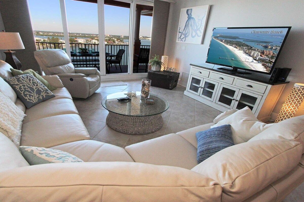 Una sala de estar con un sofá, una mesa de centro y un televisor que muestra una escena de playa.