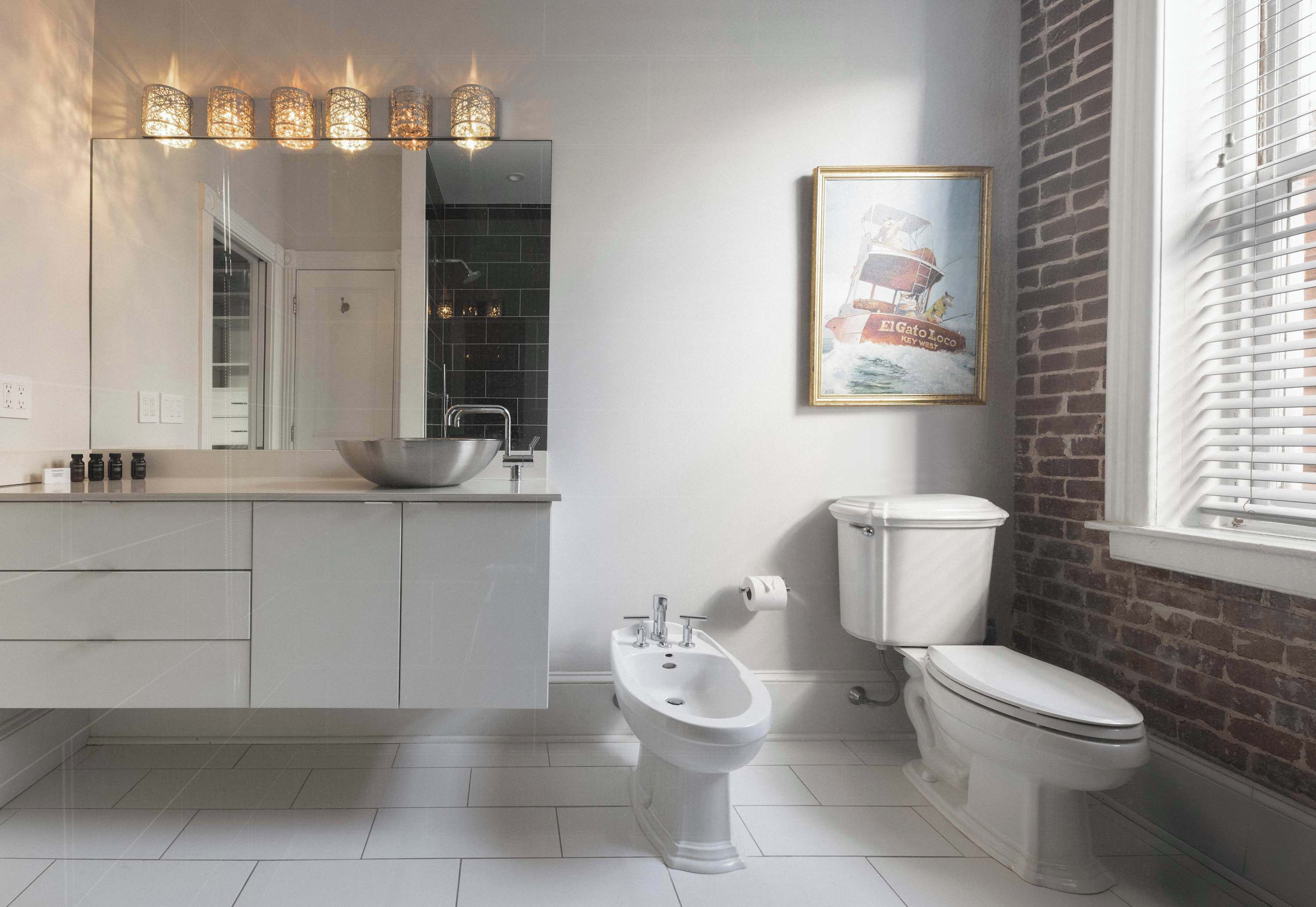 Une salle de bain moderne équipée d’un bidet, de toilettes et d’un grand miroir.