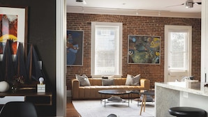 Un salon moderne avec un mur en briques, un canapé, une table basse et des œuvres d’art accrochées au mur.