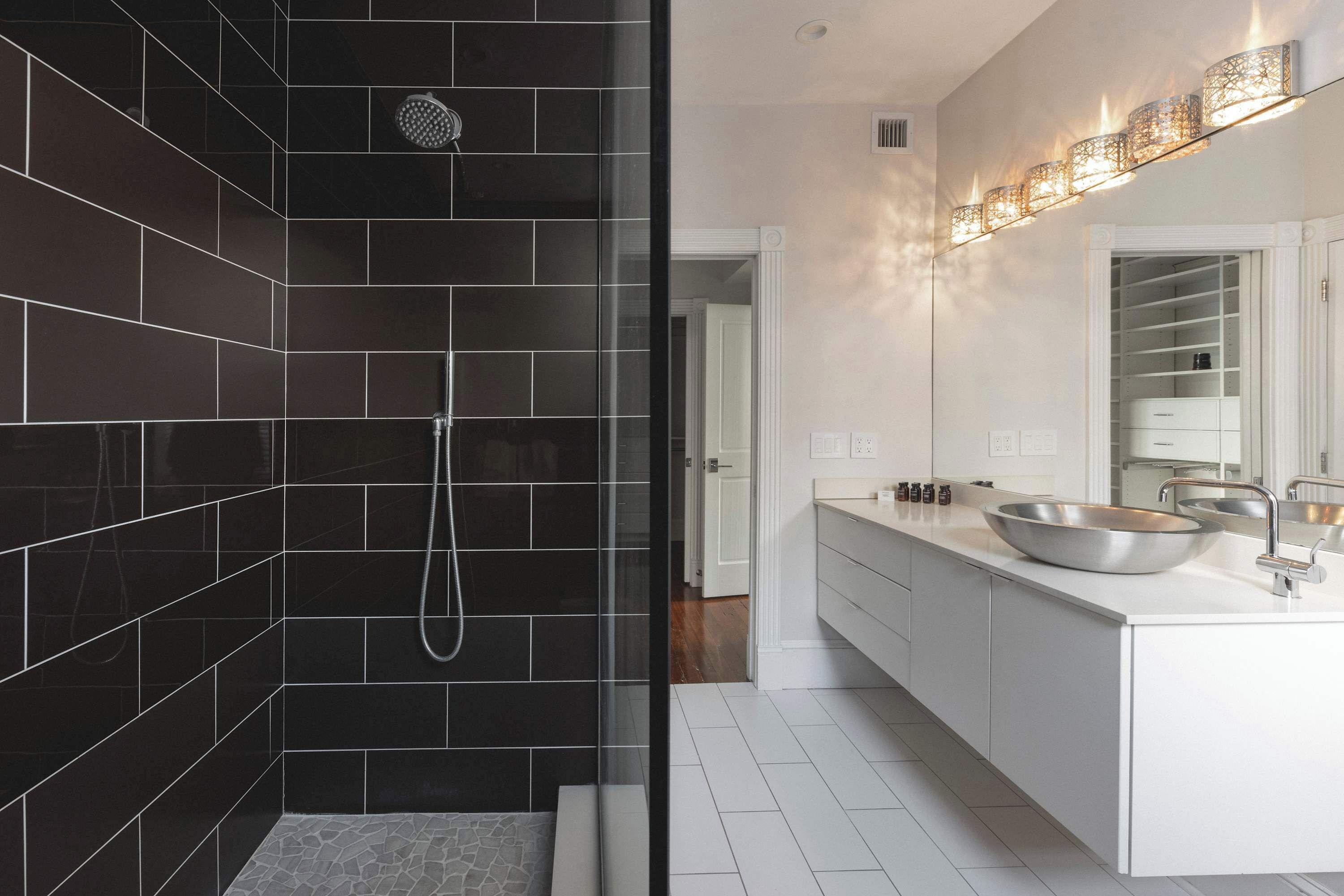 Un baño moderno con ducha envuelta en vidrio, un lavabo grande de color blanco y un espejo sobre el lavabo.