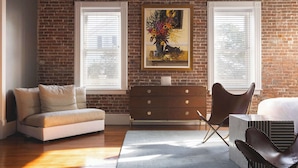 Une pièce avec un mur en briques, un canapé, une commode et une chaise.