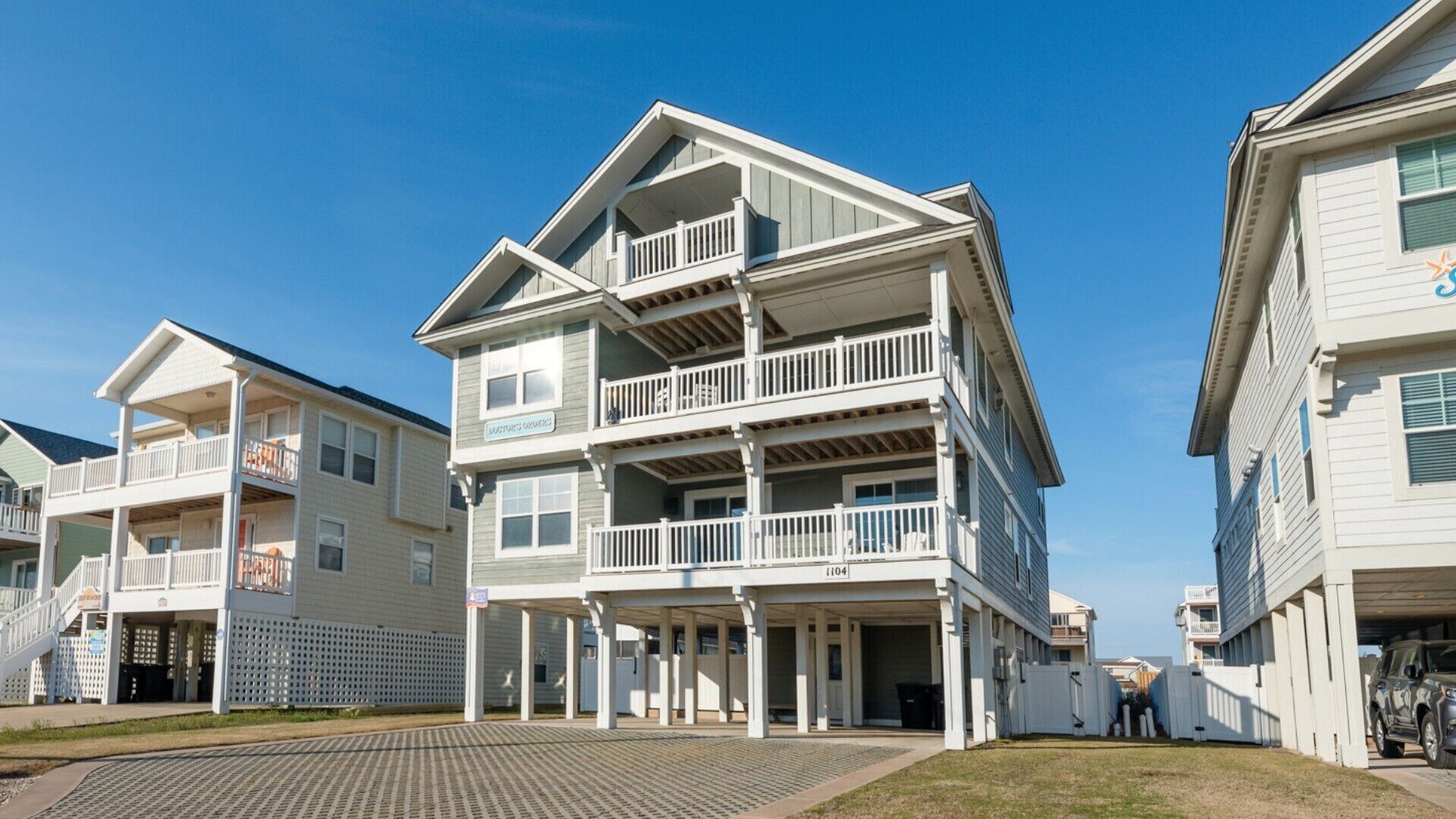 Un edificio frente al mar con varios pisos, balcones, un espacio al aire libre techado y cielo despejado.