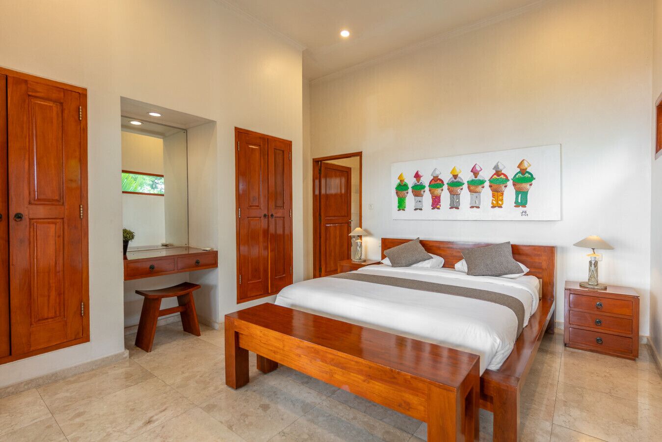 Quarto com cama grande, guarda-roupa de madeira, escrivaninha e um quadro na parede.