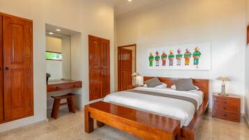 Quarto com cama grande, guarda-roupa de madeira, escrivaninha e um quadro na parede.