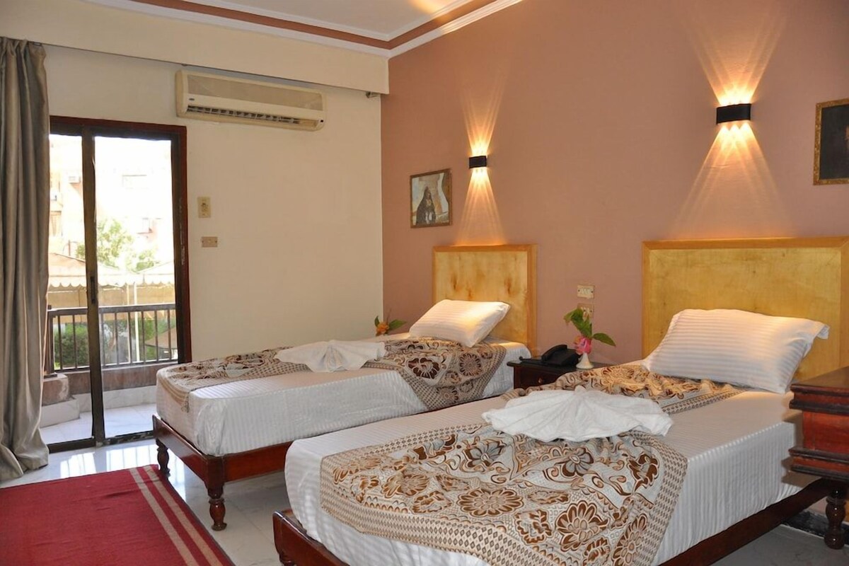 A hotel room with two beds, a balcony, and a painting on the wall.