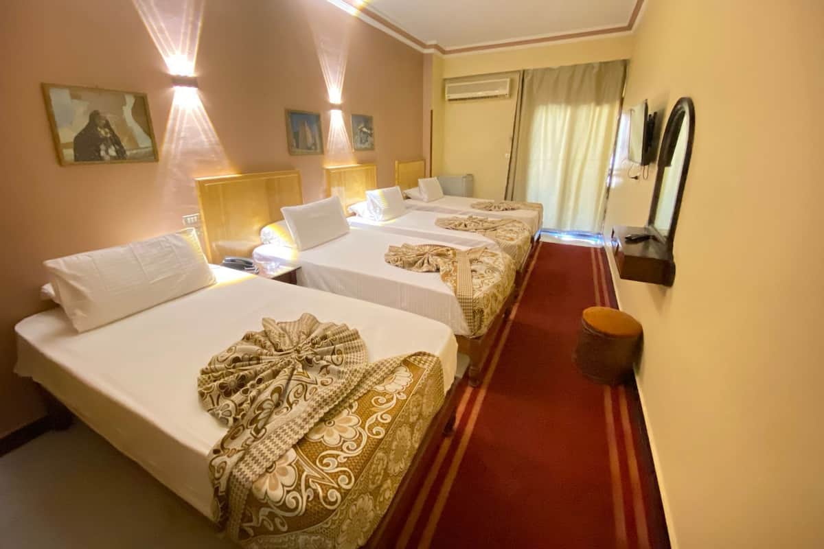 Habitación de hotel con dos camas, alfombra roja, espejo en la pared y ventana con cortinas.