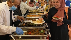 Una barra de buffet con diversos platos y un camarero sirviendo comida.