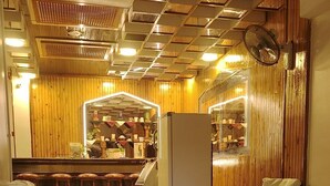 Una habitación de hotel con una cama grande, dos camas más pequeñas, una zona de bar y un espejo.