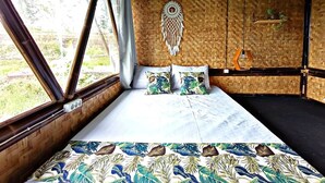 A room with a bed, a dreamcatcher, and a shelf with a plant. - Cianjur Paddies Hostel (Cianjur)