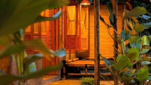 A wooden building with a thatched roof, a wooden bench, and a hanging light fixture. - Cianjur Paddies Hostel (Cianjur)