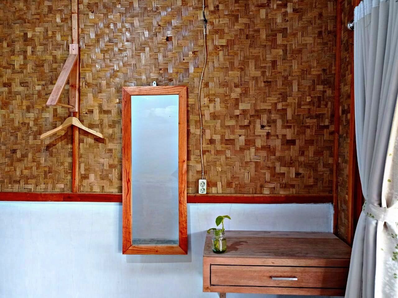 Une pièce avec une commode en bois, un miroir suspendu et une petite plante en pot.
