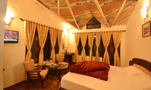 A cozy room with a bed, a chair, a small table, and curtains. - Green Oak Resort (Dhari)