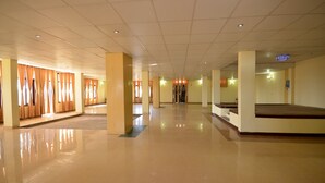 Tilava ja valoisa hotellin aula, jossa on kiillotettu lattia, suuret pylväät ja keskeisellä paikalla sijaitseva portaikko.