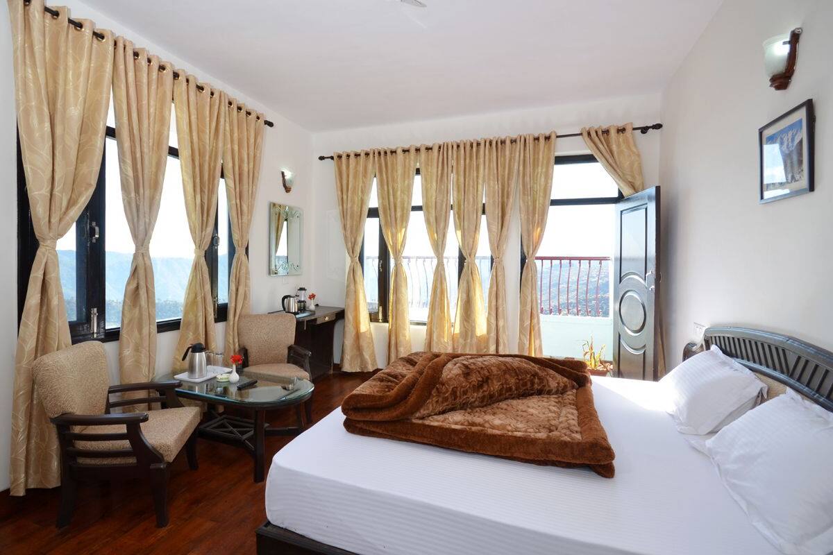 Una habitación de hotel con cama, escritorio, silla y cortinas.