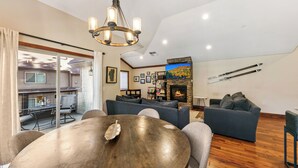 A modern living room with a round wooden table, grey sofas, and a stone fireplace. - Luxury Mountain Retreat | Walk to Heavenly | TW504 (South Lake Tahoe)