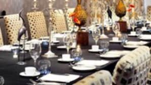 A dining room with a long table set for a meal, featuring candles, glassware, and a vase with flowers. - Ardington Hotel (Worthing)