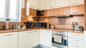 Une cuisine moderne avec des armoires blanches, un four en acier inoxydable, une machine à café et un four à micro-ondes.