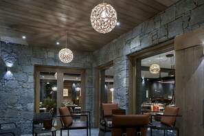 An interior with stone walls, wooden ceiling, and modern pendant lighting.