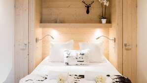 A wooden-paneled bedroom with a bed, white bedding, and a mounted deer head. - Mammoth Lodge Apartment T3 Cabin D09 (Courchevel)