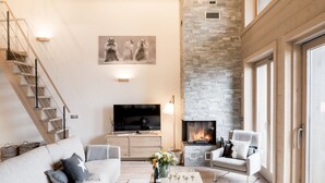 Una sala de estar moderna con chimenea, un conjunto de sofás, una mesa de centro con bebidas y un televisor.