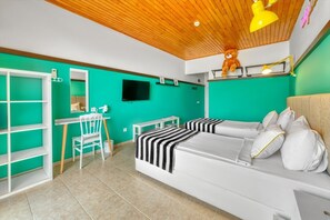 A room with a bed, a desk, a chair, a television, and a shelf with a teddy bear.