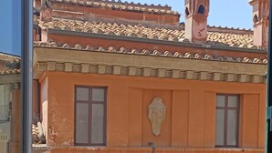 A building with a weathered orange facade, a tiled roof, and two windows with shutters. - Biancoreroma B&B (Rome)