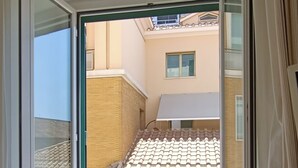 A room with a large window, a built-in air conditioning unit, and a view of neighboring buildings. - Biancoreroma B&B (Rome)