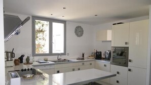 A modern kitchen with white cabinets, a built-in oven, and a window providing natural light. - Les Algues du Grau (Agde)