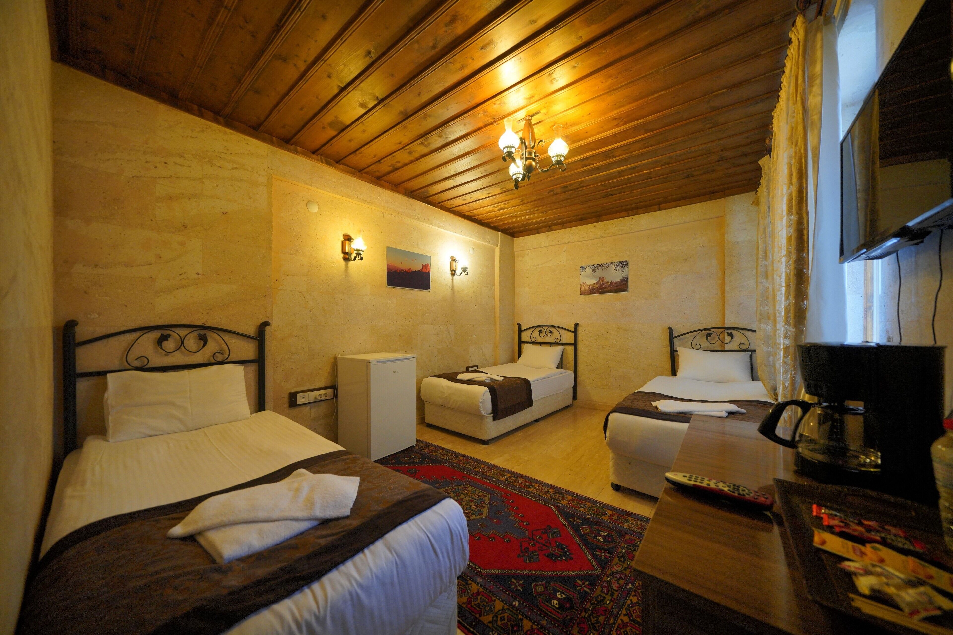 A hotel room with two beds, a coffee maker, and a TV.