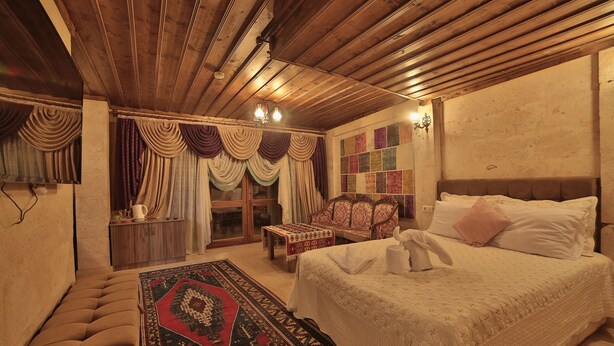 Una habitación tradicional con una cama, un banco, un tapiz estampado y techo de madera.