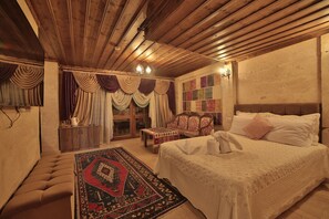 A traditional room with a bed, a bench, a patterned rug, and a wooden ceiling. - Göreme Cave Rooms (Nevsehir)