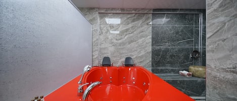 A modern bathroom with a heart-shaped bathtub, a glass shower enclosure, and marble walls.