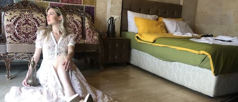 Una habitación con cama, mesita de noche, lámpara y una alfombra estampada.