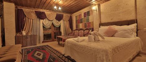 Un dormitorio con una cama grande, techo de madera, alfombra colorida y pared con diseño de colcha.