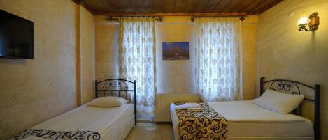 A room with two single beds, a television on the wall, and a picture of a landscape.