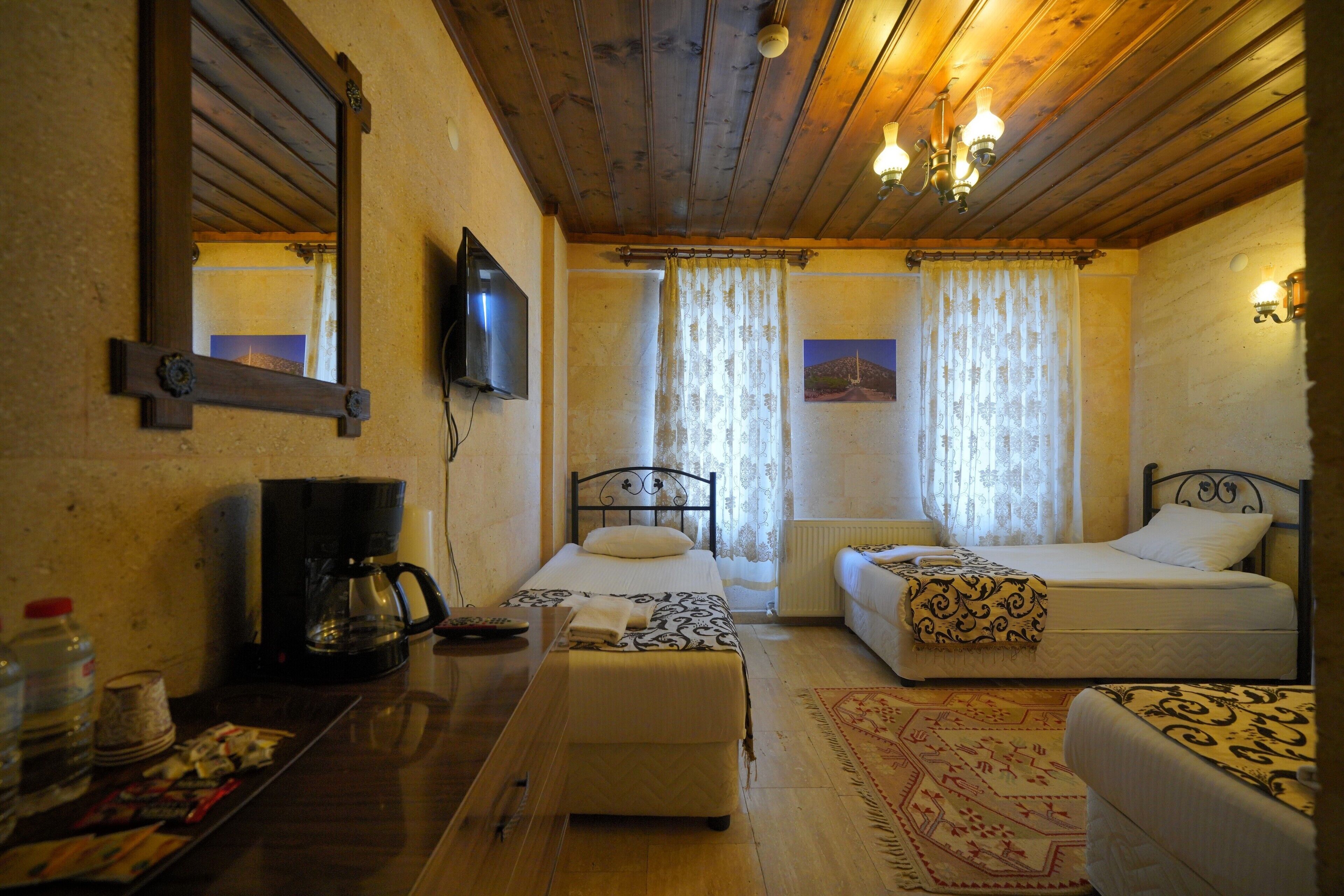 A room with two beds, a television, a coffee maker, and a table with various items.