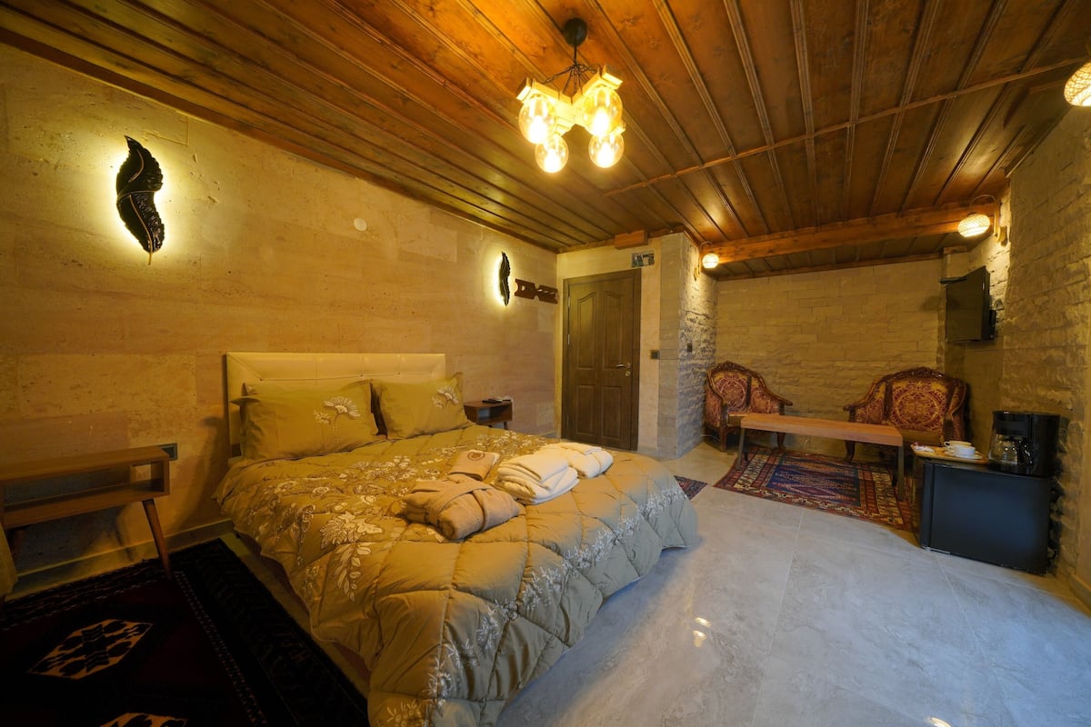 A cozy bedroom with a large bed, a wooden ceiling, and a small table with chairs.