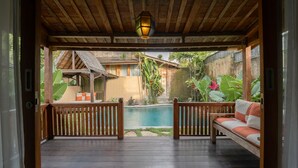Una terraza de madera con piscina, un banco de madera y un farol colgante.