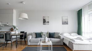 Un soggiorno moderno e minimalista con un divano, un tavolo da pranzo e un letto.