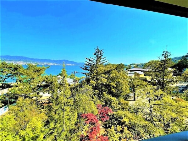 A view of a coastal area with dense greenery and a clear blue sky. - Miyajima MorinoYado Inn (Hatsukaichi)