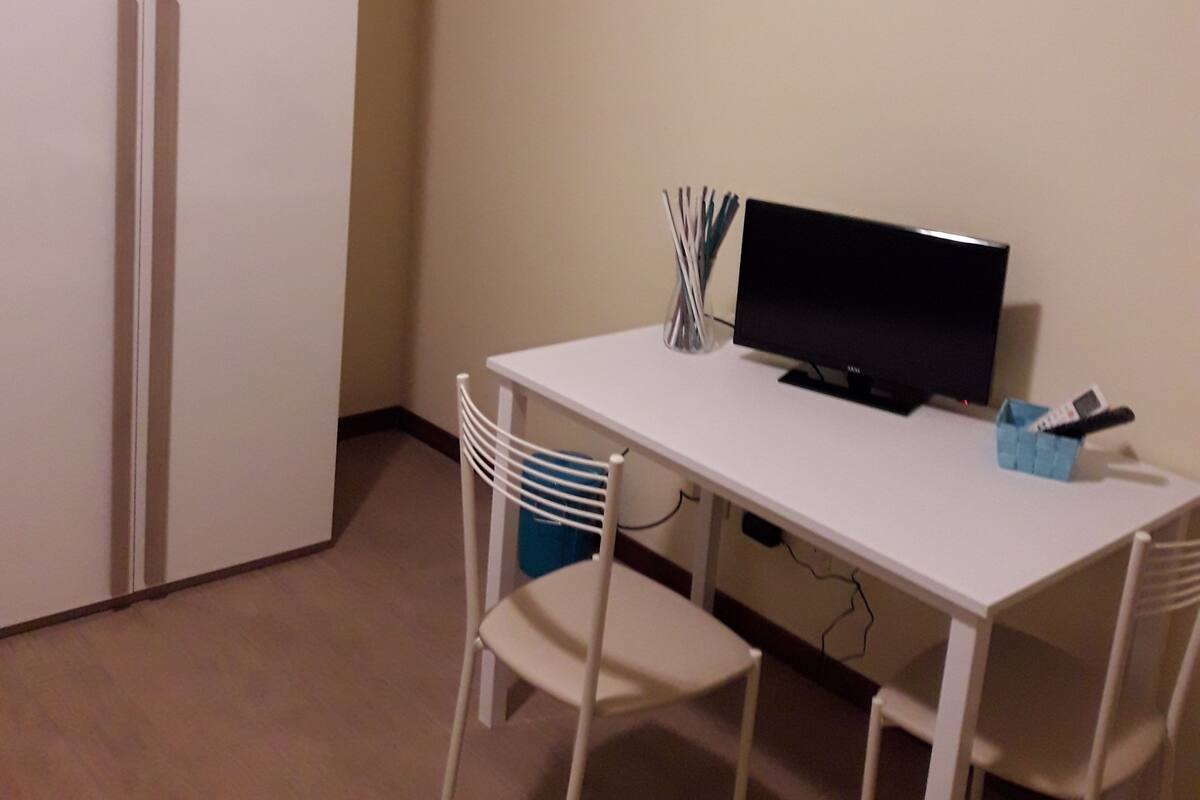 A room with a white desk, a black monitor, and a white chair.
