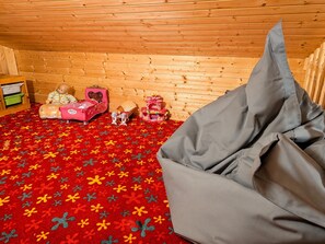A room with a red patterned carpet, a grey bean bag, and wooden walls.