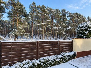 Schneebedeckte Landschaft mit Holzpflanz und einem Gebäude im Hintergrund.