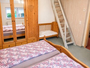 A bedroom with a bed, a wardrobe, a window, and a ladder.