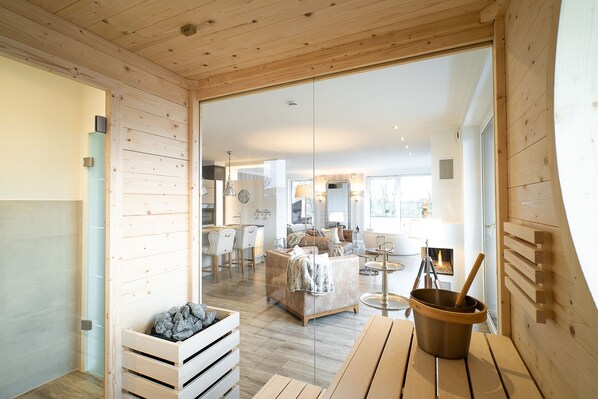 A modern interior with wooden walls, a sofa, a dining table, and a fireplace.