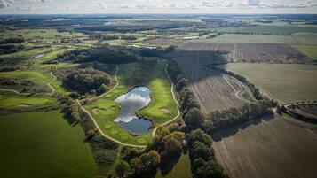 An aerial view of a golf course with multiple holes, water bodies, and surrounding fields.