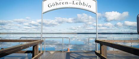 A pier with a sign reading "SCHIFFSANLEGER GÖHREN-LEBBIN" and a view of the water and sky.
