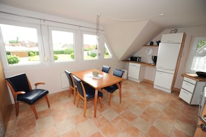 A dining area with a table and chairs, a kitchen with appliances, and large windows with a view.