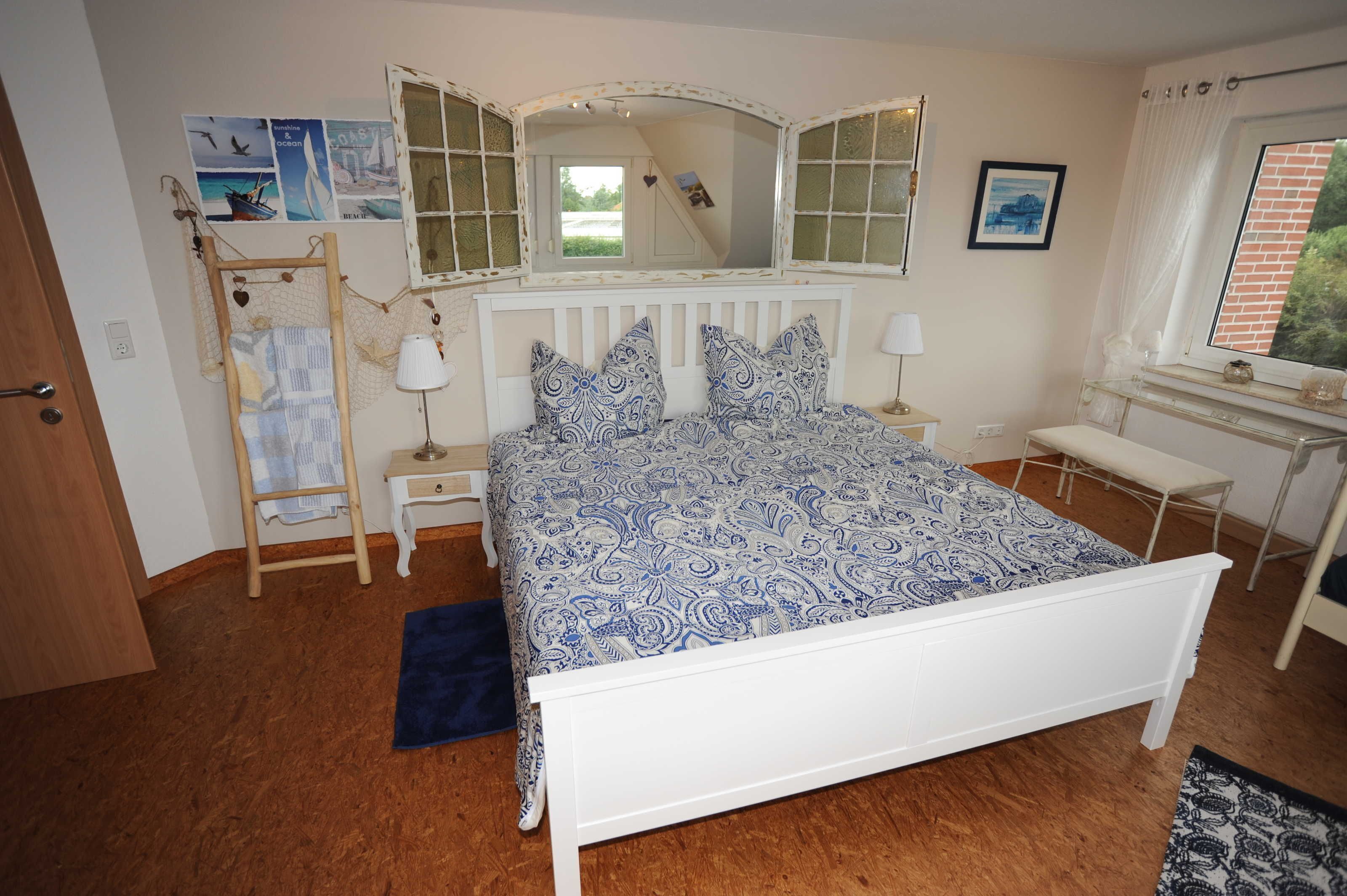A bedroom with a bed, bedside tables, a mirror, a window, and a door.
